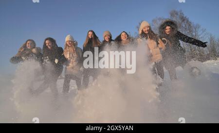 Amici delle ragazze allegre calciare la neve con i loro piedi. Foto Stock