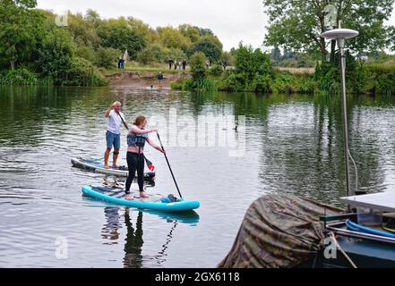 Due pedalò, un uomo una donna che si addica sul Tamigi a Shepperton Surrey England UK Foto Stock