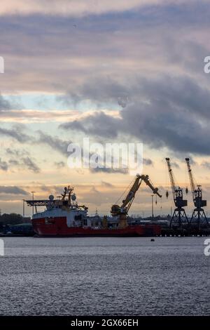 tramonta sulle banchine militari in legno di marchwood nei moli di southampton o sul porto di southampton con gru da cantiere in silhouette contro un cielo serale. Foto Stock
