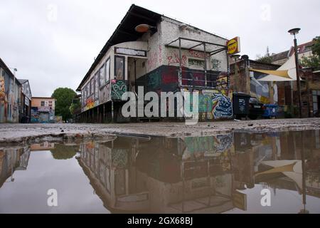 La foto mostra un luogo perduto nella città di Berlino. Tra tutta la sporcizia, vecchi mattoni e graffiti c'è una vecchia strada con una pozzanghera. Foto Stock