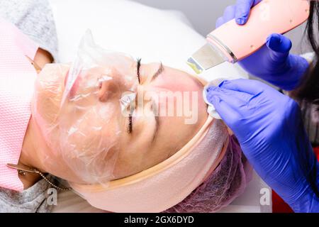 Pulizia del viso da epitelio cheratinizzato, grasso in eccesso, blocchi delle ghiandole sebacee, comedoni. Pulizia del viso con uno scrubber ultrasonico Foto Stock