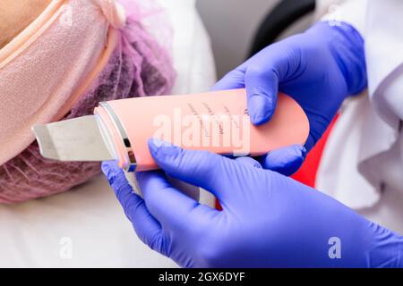 Pulizia del viso da epitelio cheratinizzato, grasso in eccesso, blocchi delle ghiandole sebacee, comedoni. Pulizia del viso con uno scrubber ultrasonico Foto Stock