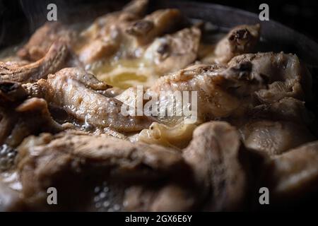 Le ali di pollo vengono cotte nel proprio succo in una padella Foto Stock