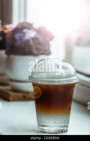 Un tonico freddo espresso in un vetro di plastica si siede su un davanzale in una caffetteria. Foto Stock