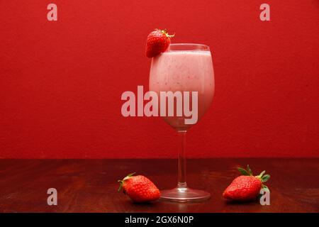 Cocktail fruttato servito con fragole fresche su sfondo rosso Foto Stock