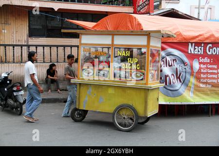 Un venditore di strada di cibo con un carrello che vende il sup daging o zuppa di carne, nasi goreng ayam o pollo fritto riso a Bukittinggi, Indonesia.