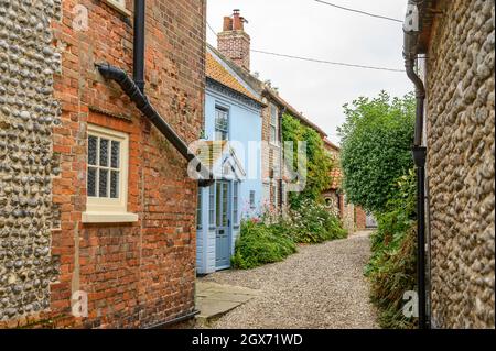 High Street nel villaggio di Blakeney è una strada affascinante con le case d'epoca con facciate in mattoni o selce renderizzate piene di carattere, Norfolk, Inghilterra. Foto Stock