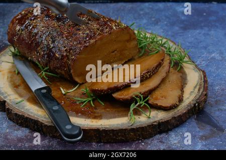 Seitan arrosto strofinato con spezie e salsa barbecue su tavola di legno, affettato, spazio copia Foto Stock