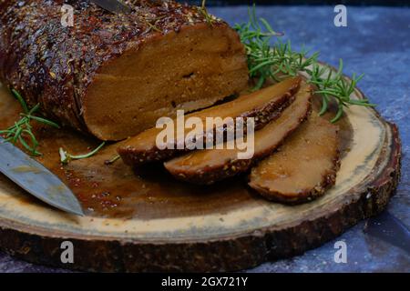 Seitan arrosto strofinato con spezie e salsa barbecue su tavola di legno, affettato, spazio copia Foto Stock