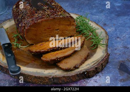 Seitan arrosto strofinato con spezie e salsa barbecue su tavola di legno, affettato, spazio copia Foto Stock
