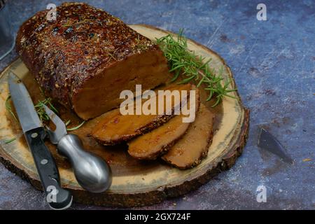 Seitan arrosto strofinato con spezie e salsa barbecue su tavola di legno, affettato, spazio copia Foto Stock