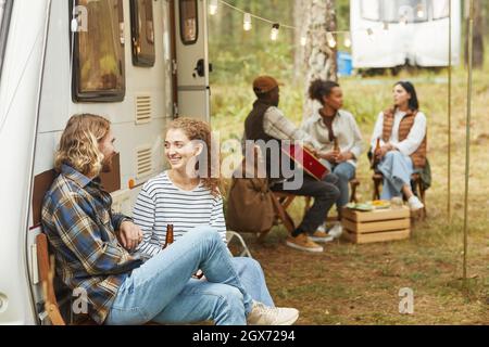 Gruppo di giovani che si rilassano all'aperto in camper in autunno, spazio copia Foto Stock