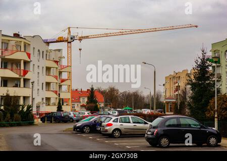 POZNAN, POLONIA - 25 gennaio 2015: Auto parcheggiate su una strada con edifici di appartamenti e gru da cantiere Foto Stock