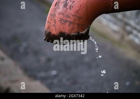 Goccioline d'acqua fluiscono dal vecchio tubo arrugginito. Scarsità d'acqua sul pianeta. Concetto di inquinamento del suolo e problemi di fonti fossili. Foto Stock