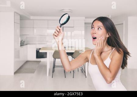 Home ispezione divertente appaltatore o ispettore donna cercando con lente di ingrandimento per vizio nascosto, danni all'acqua, muffa, crepe nel soffitto Foto Stock