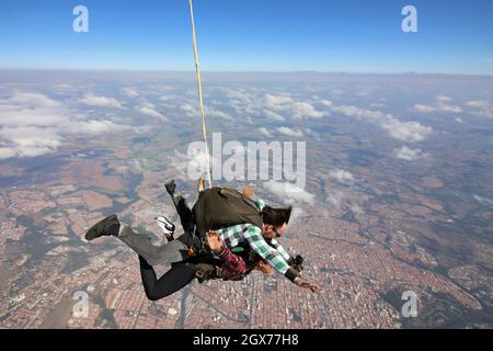 Salto in paracadute tandem. Bella donna brasiliana. Foto Stock