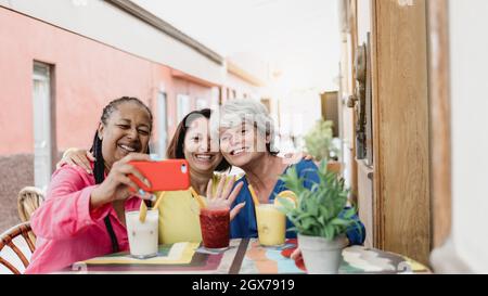Felice multirazziale anziani amici che fanno videochiamata con il telefono cellulare al ristorante brunch - persone di generazione anziana che si divertono Foto Stock