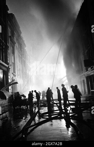 Vigili del fuoco che sparano acqua sugli edifici in fiamme durante il London Blitz Foto Stock