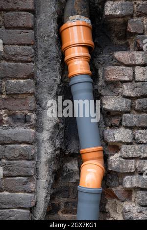 Sistema di drenaggio fisso pronto all'uso da tubi in plastica realizzati in idraulico nella parete del vecchio edificio in Europa. Concetto di ingegneria delle costruzioni Foto Stock