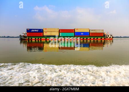 Chiatta che viaggia sul fiume Mekong che trasporta i contenitori di spedizione Foto Stock