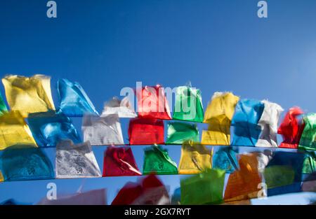 Le bandiere di preghiera tibetane buddiste ondolano nel vento Foto Stock