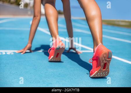 Sprinter in attesa di inizio gara su piste da corsa allo stadio all'aperto. Atleta di atleta sportiva e fitness su pista blu con running arancione Foto Stock