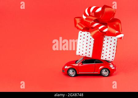 Mosca, Russia, 14 gennaio 2021. Design minimal per celebrare natale o biglietto di auguri di Capodanno. Concetto di consegna del regalo. Piccola auto giocattolo rossa con Foto Stock