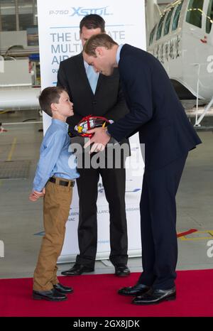 Il Principe William, Duca di Cambridge riceve un regalo da un ragazzo durante una visita al Pacific Aerospace di Hamilton, Nuova Zelanda Foto Stock