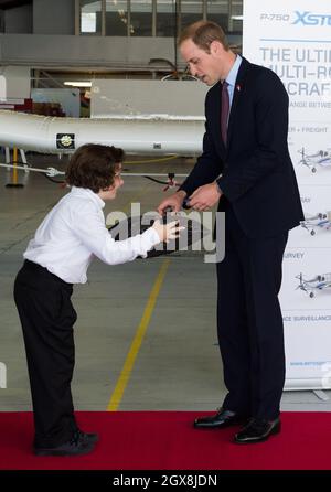 Il Principe William, Duca di Cambridge riceve un regalo da un ragazzo durante una visita al Pacific Aerospace di Hamilton, Nuova Zelanda Foto Stock