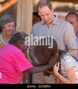 Il Principe William, Duca di Cambridge guarda come Caterina, Duchessa di Cambridge viene presentata con una collana durante una visita ad un centro culturale locale in Uluru, Australia. Foto Stock