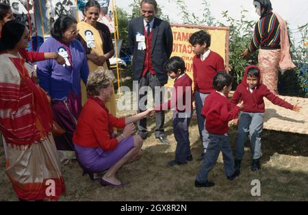 Diana, Principessa del Galles, indossando un abito rosso e viola di Catherine Walker, si piega a chiacchierare con i bambini durante una visita ad Agra, India il 11 febbraio 1992 . Foto Stock
