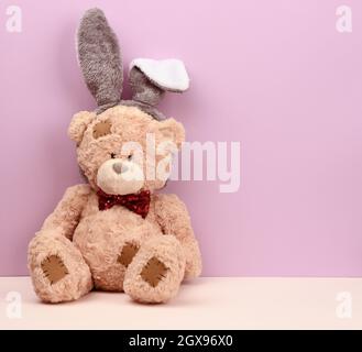 Simpatico orso bruno con maschera di coniglio e lunghe orecchie sulla testa, divertente carta di Pasqua per le vacanze Foto Stock