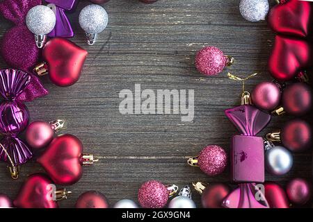 Cornice di invito di Natale fatta di giocattoli di Capodanno, cuori e palle su superficie di legno. Composizione a strato piatto per tessera vacanza invernale. Invito Foto Stock