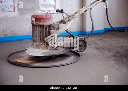 macchina professionale per l'esecuzione e la lucidatura del pavimento del massetto di sabbia e cemento sul cantiere di un nuovo appartamento a due piani. Sabbia e cemento Foto Stock