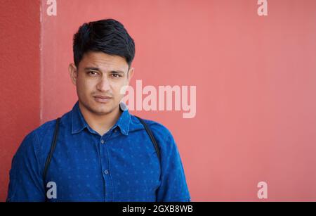 ritratto di affari di avvio di un uomo d'affari indiano casual con una camicia blu e uno zaino davanti alla parete rosa Foto Stock