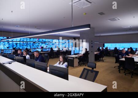 Gruppo di operatori di data center di sicurezza che lavorano in una sala di monitoraggio TVCC che cerca più monitor funzionari che monitorano più schermi per il sospetto Foto Stock