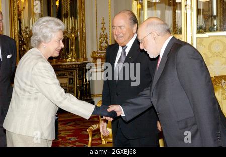 La Regina Elisabetta II della Gran Bretagna incontra il presidente della Football Association Geoffrey Thompson (a destra) e il presidente della FIFA Sepp Blatter durante un ricevimento a Buckingham Palace a Londra per celebrare il centenario del corpo di governo del gioco in tutto il mondo. Â Anwar Hussein/allactiondigital.com Foto Stock