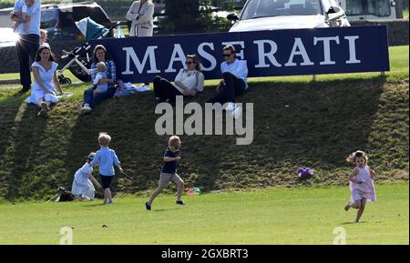 Catherine, Duchessa di Cambridge (a sinistra) si rilassa su una banca d'erba mentre osserva la principessa Charlotte di Cambridge e il principe George di Cambridge giocare insieme durante la Maserati Royal Charity Polo al Beaufort Polo Club vicino Tetbury il 10 giugno 2018. Foto Stock