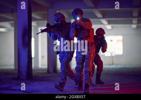 i soldati della guerra moderna squadra in formazione tattica hanno azione urbano ambiente illuminazione colorata Foto Stock