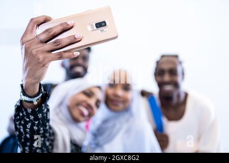 Felice gli studenti africani prendendo una foto selfie mentre in piedi insieme contro uno sfondo bianco le ragazze che indossano traidiional musulmana sudanese hijab fashion Foto Stock