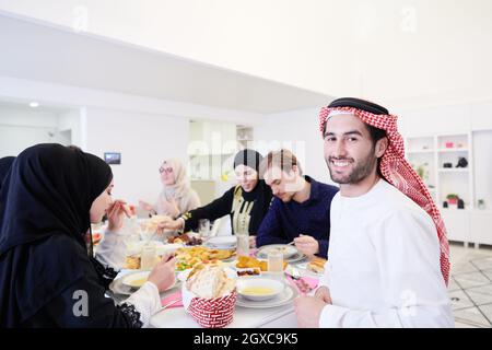 Giovane uomo arabo con cena Iftar con famiglia musulmana mangiare cibo tradizionale durante il mese di festa Ramadan a casa. Il pasto Islamico Halal e D. Foto Stock