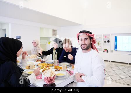 Giovane uomo arabo con cena Iftar con famiglia musulmana mangiare cibo tradizionale durante il mese di festa Ramadan a casa. Il pasto Islamico Halal e D. Foto Stock