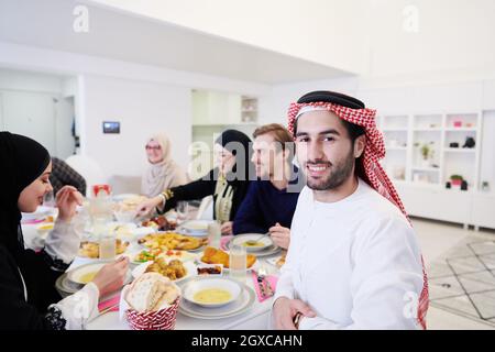 Giovane uomo arabo con cena Iftar con famiglia musulmana mangiare cibo tradizionale durante il mese di festa Ramadan a casa. Il pasto Islamico Halal e D. Foto Stock