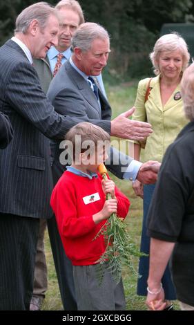 Il Principe Carlo, Principe di Galles incontra la gente mentre Stanley, un allievo della Scuola primaria di Avening nel Gloucestershire, munges su una carota alla fattoria domestica, Highgrove. Il principe del Galles ha detto che è stata una "tragedia” che una generazione di bambini sta crescendo con poca idea di dove il cibo che mangiano viene. Charles ha avvertito che i giovani allevati nelle città sono allarmante ignoranti della campagna e di come il cibo è prodotto. Foto Stock