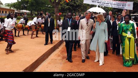 Il Principe Carlo, il Principe del Galles e Camilla, la Duchessa della Cornovaglia sono accolti dai ballerini che arrivano alla St. Joseph's School di Naggalama, Uganda Foto Stock