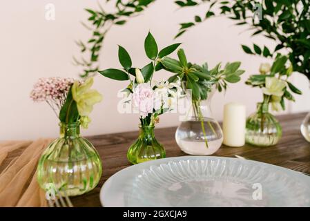 Molti vasi di vetro con fiori nella cornice del tavolo festivo. Messa a fuoco selettiva Foto Stock