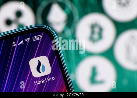 Huobi è uno scambio di criptovaluta. App Huobi sullo schermo dello smartphone sullo sfondo delle principali criptovalute. Foto Stock