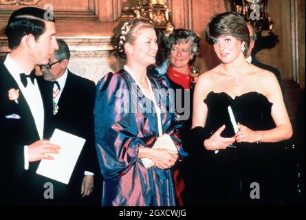 **FOTO DEL FILE** Lady Diana Spencer, in seguito diventata Diana, Principessa del Galles, imposta i flashbulb che spuntano mentre indossa un vestito nero Emanuel rivelante partecipando al suo primo fidanzamento ufficiale con il Principe Carlo, e la Principessa Grace di Monaco, ad un concerto di raccolta fondi presso la Goldsmiths Hall di Londra nel marzo 1981. I designer Elizabeth e David Emanuel hanno in mano un'asta di abiti indossati dalla compiuta principessa Diana. Gli abiti saranno destinati all'asta l'8 giugno 2010 a Londra, presso le aste specializzate di moda d'epoca Kerry Taylor Auctions. Foto Stock