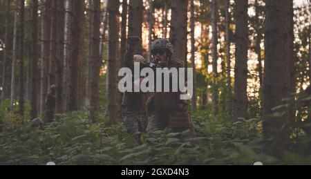 il soldato moderno della guerra sta mostrando i segnali tattici della mano per dare silenziosamente ordini e i generatori per l'ambiente della foresta della squadra Foto Stock