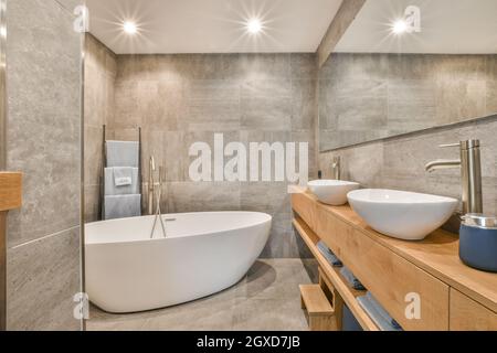 Interno di un elegante bagno con lavelli bianchi puliti e vasca in appartamento di lusso Foto Stock